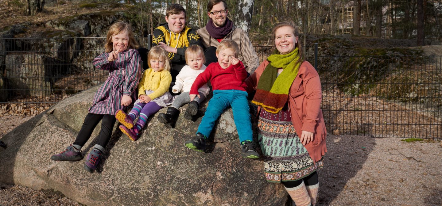 suurperheestä kuva istumassa isolla kivellä puistossa