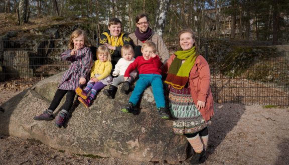 suurperheestä kuva istumassa isolla kivellä puistossa