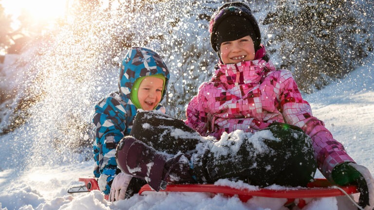 kaksi lasta leikkivät lumessa
