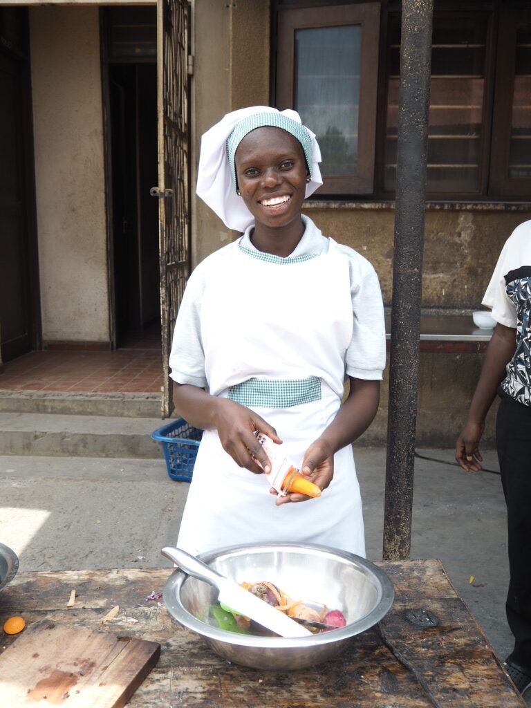 Tansanialainen kokiksi opiskeleva Alice kuorii porkkanaa.