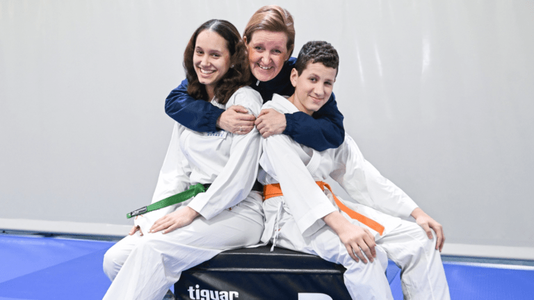 Äiti, Marja-Terttu, halaa lapsiaan Sonyaa ja Samia, jotka ovat pukeutuneet karateasuihin.