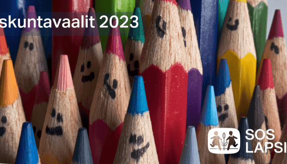 Kuva, jossa teksti Eduskuntavaalit 2023 ja erivärisiä puukyniä , joihin on piirretty ilmeet. Alakulmassa SOS-Lapsikylän logo.
