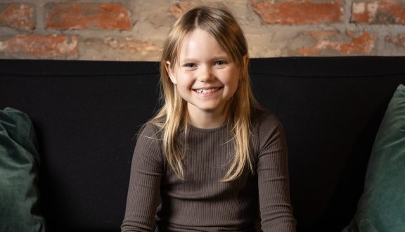 Iloinen tyttö katsoo suoraan kameraan.