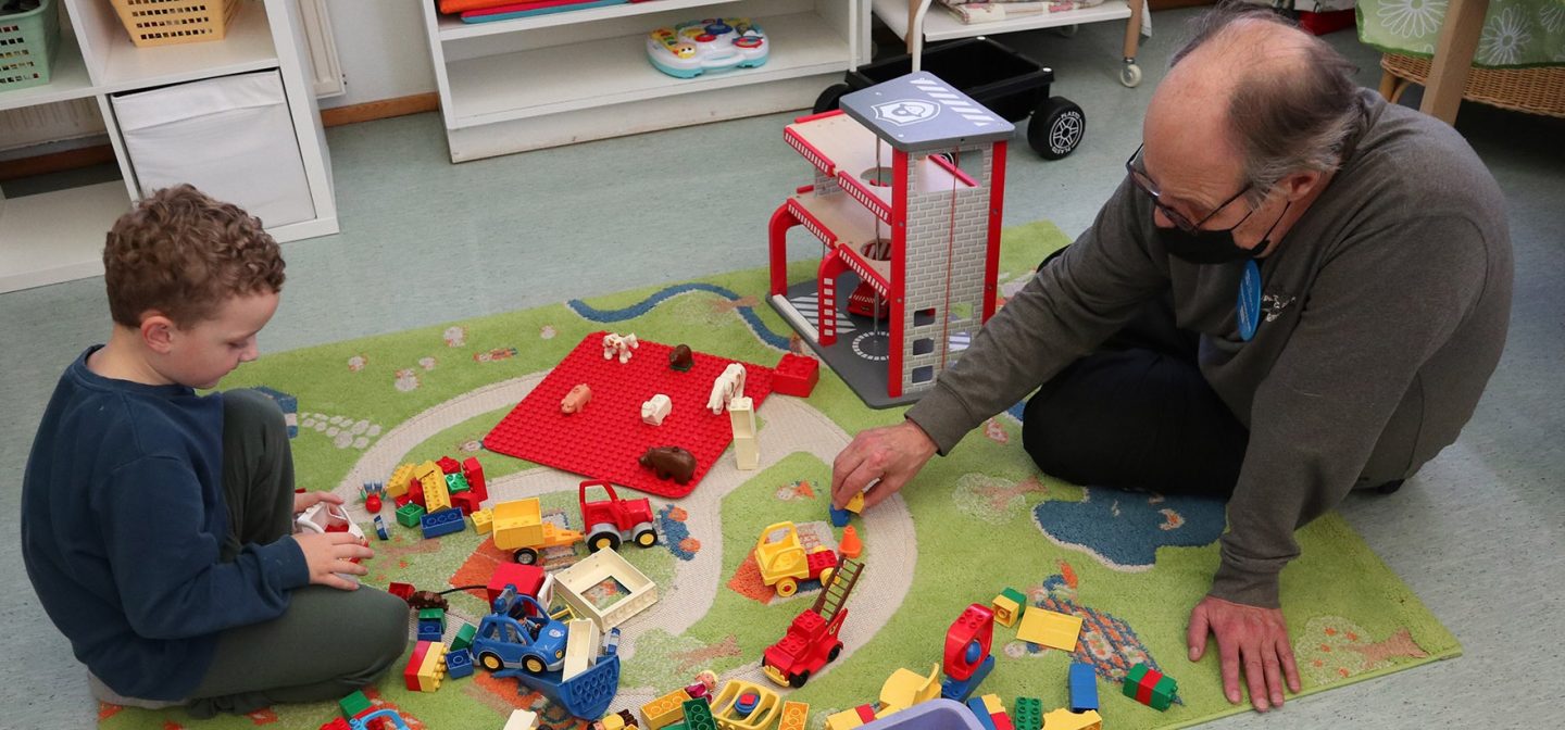 poika ja vanhempi mies leikkivät legoilla matolla