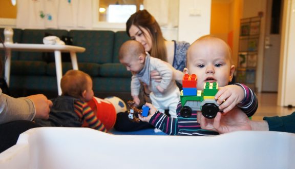 Lapsi leikkii, taka-alalla 'iti toisen lapsen kanssa
