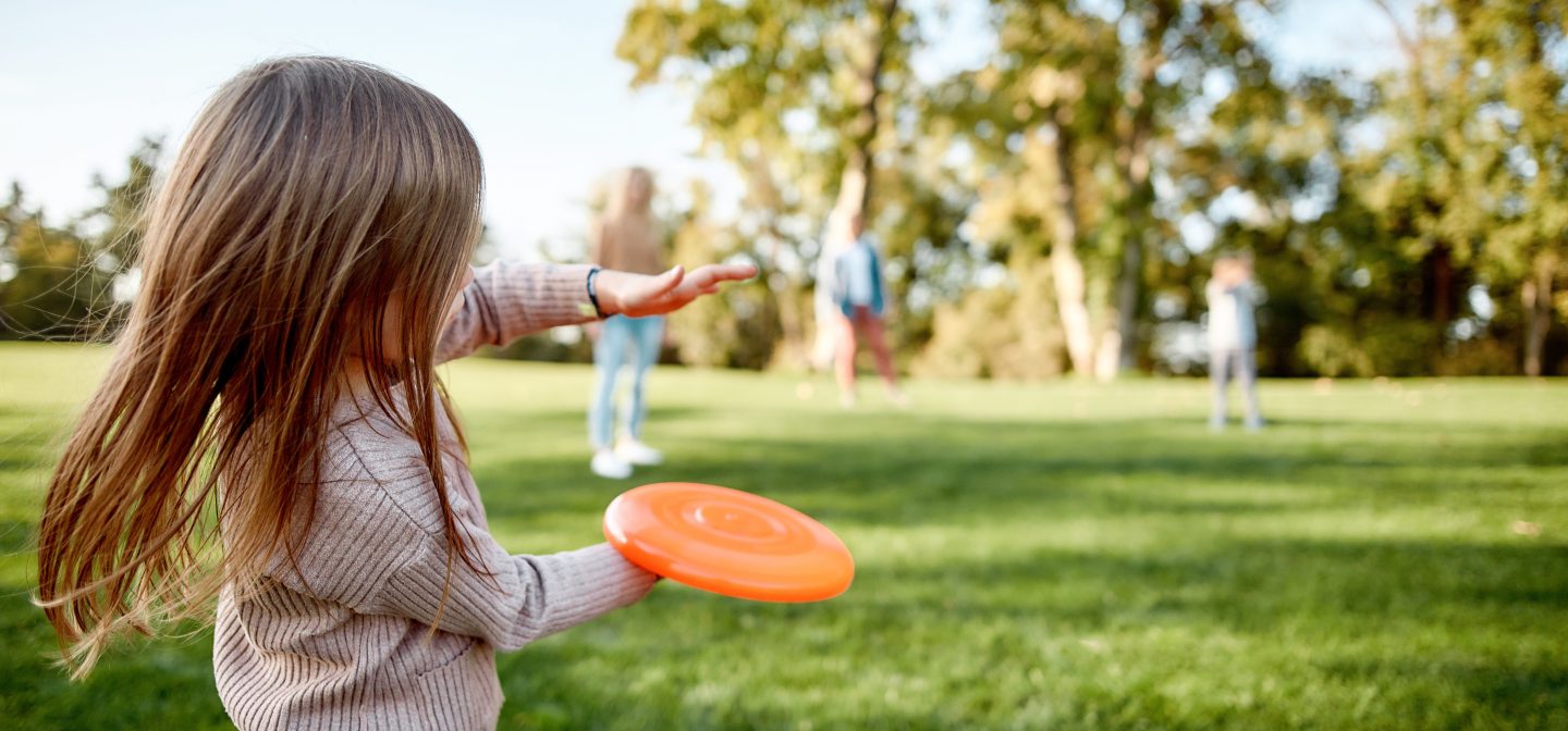 Pieni tyttö heittää perheelle frisbeetä.