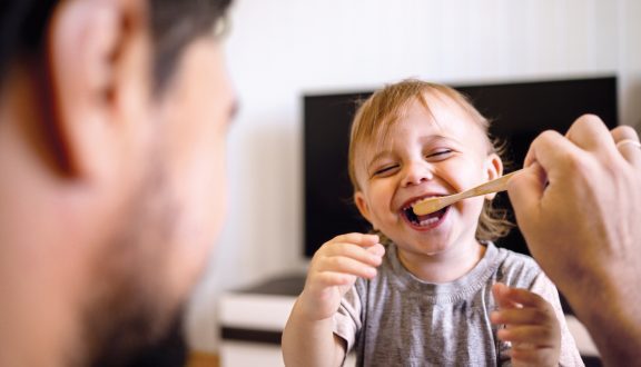 Isä auttaa pientä poikaa pesemään hampaansa. Isä huolehtii lapsesta.