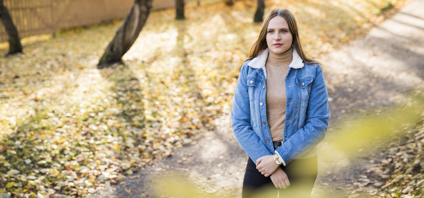 tyttö kävelee ulkona. keltaisia puun lehtiä maassa ja puita taustalla