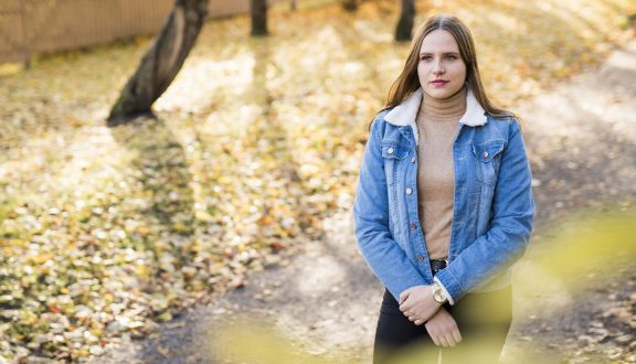 tyttö kävelee ulkona. keltaisia puun lehtiä maassa ja puita taustalla