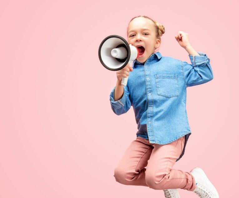 Tyttö hyppää heiluttaen kättään ja huutaen mikrofooniin