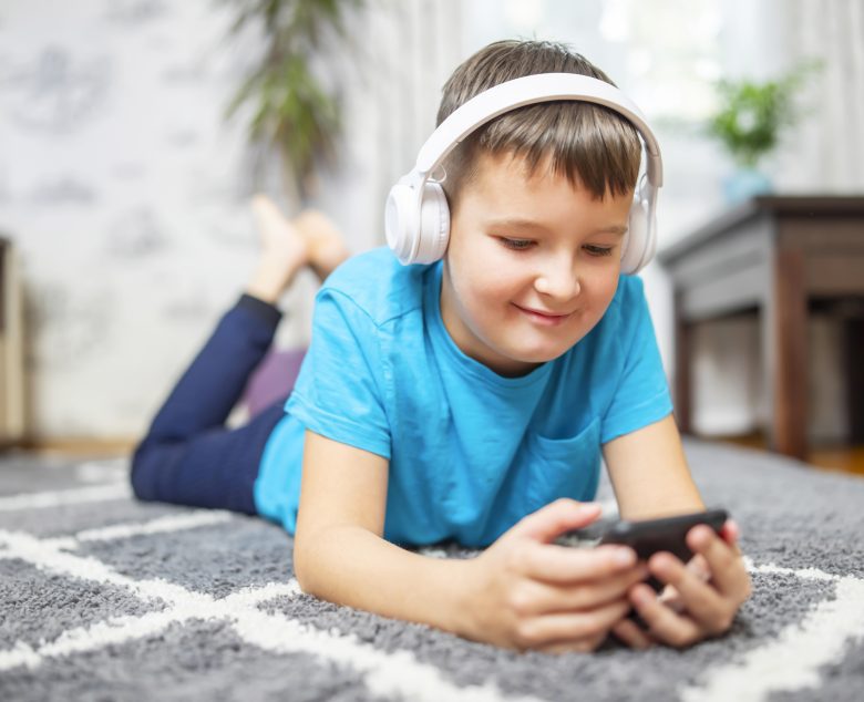 Lapsi kuulokkeet päässä on puhelimella