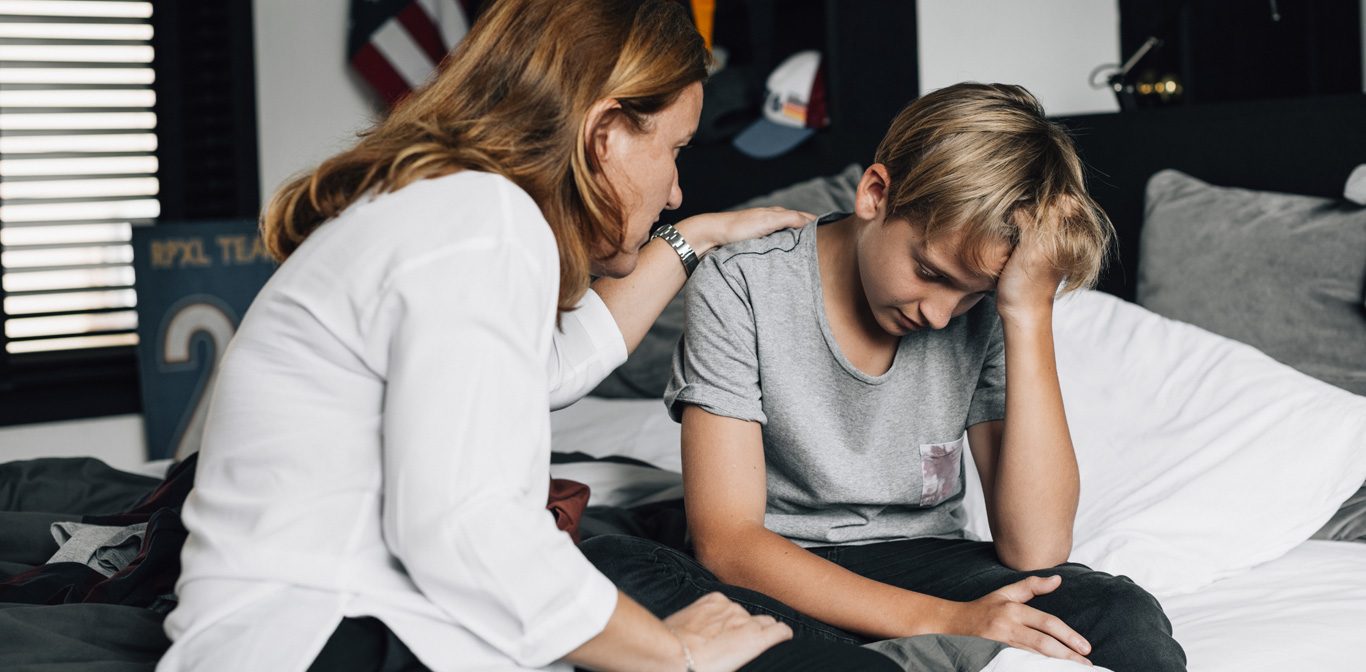 Nainen lohduttaa nuorta poikaa pojan huoneessa