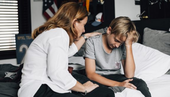 Nainen lohduttaa nuorta poikaa pojan huoneessa