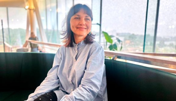 Lets'chat vapaaehtoinen Olena istuu sohvalla ja hymyilee.