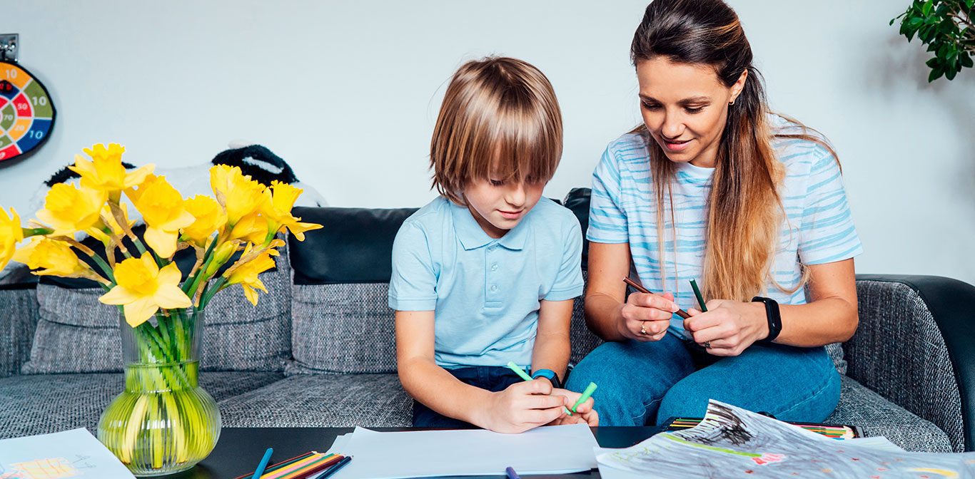 Lapsi ja nainen istuvat sohvalla ja piirtävät.