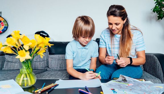 Lapsi ja nainen istuvat sohvalla ja piirtävät.