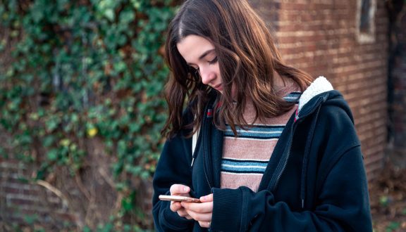 Teini katselee kännykkää ulkona.